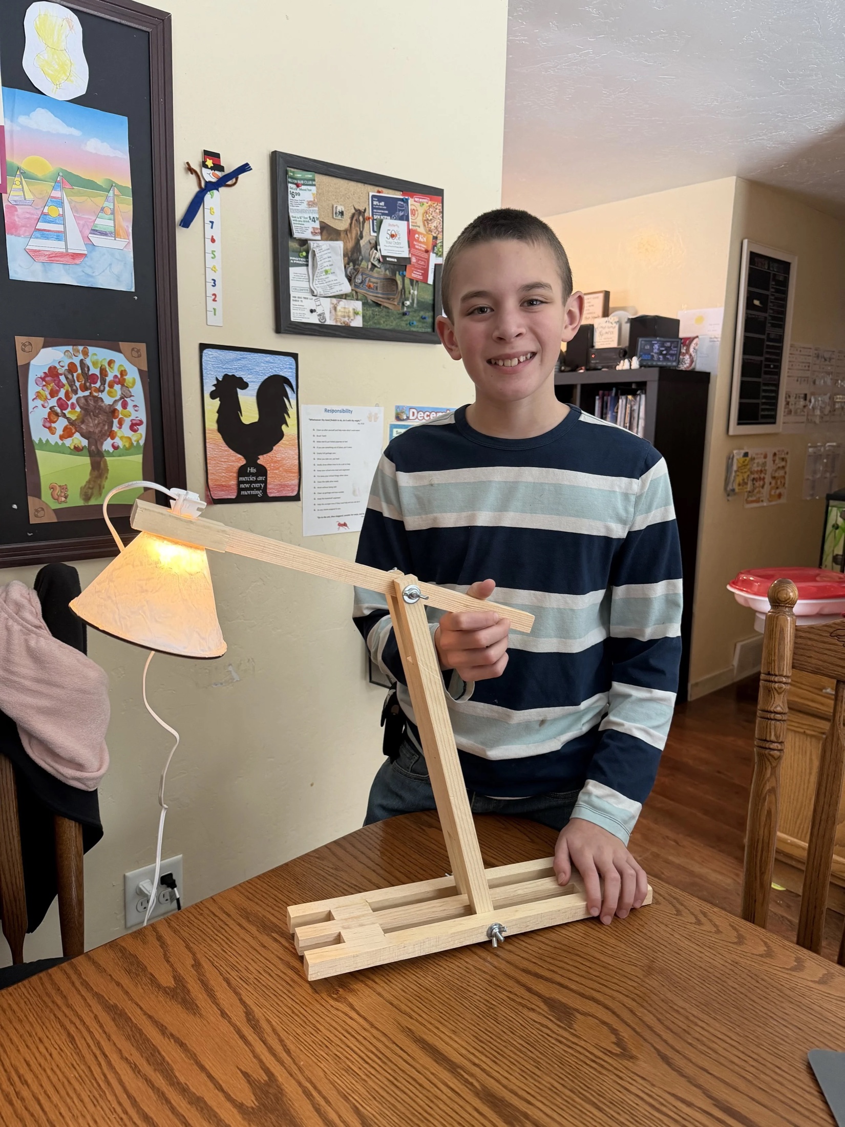 A learner at home with a completed articulating wooden lamp