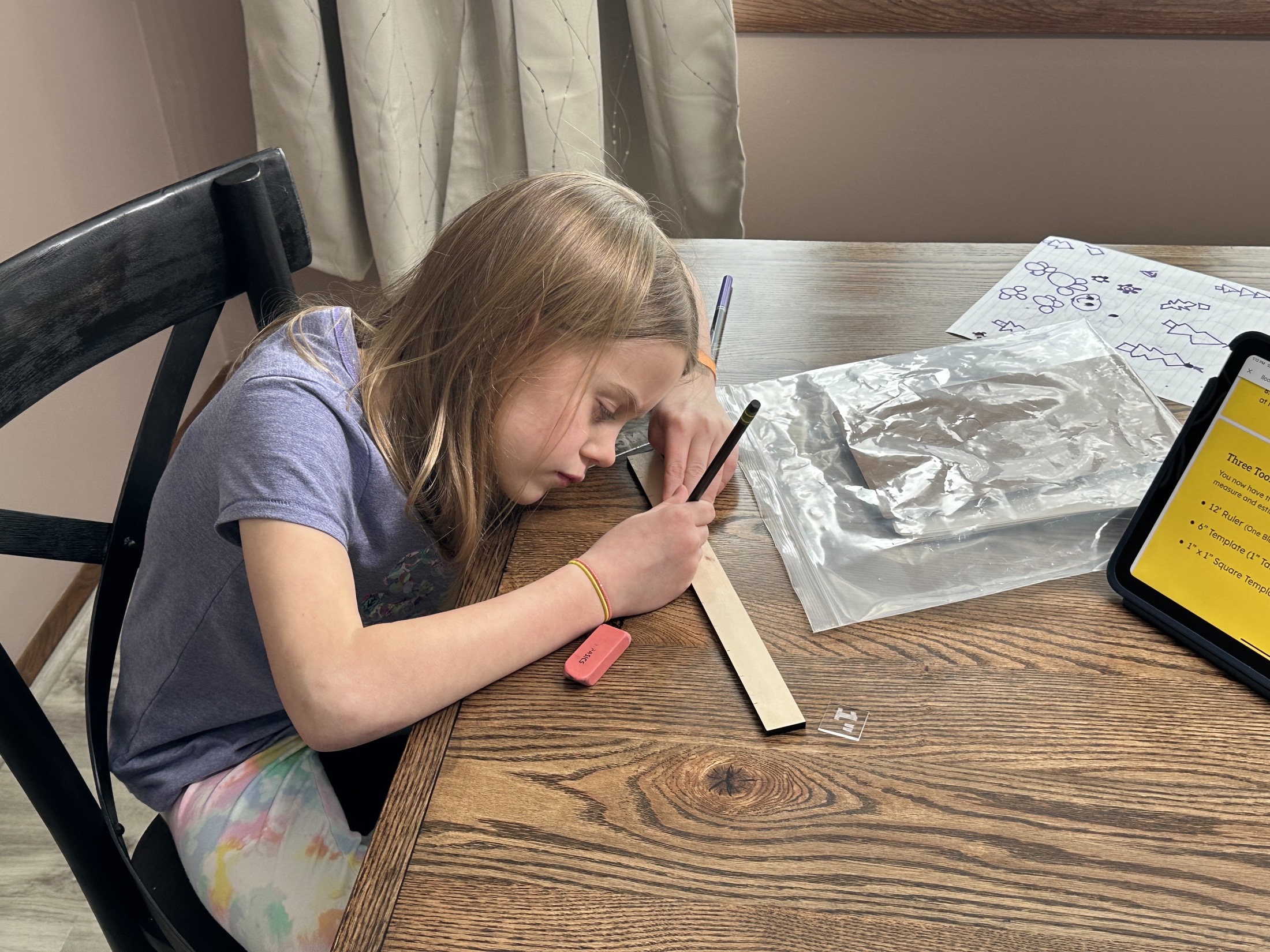 A learner measuring and marking wood while following the lesson on a tablet